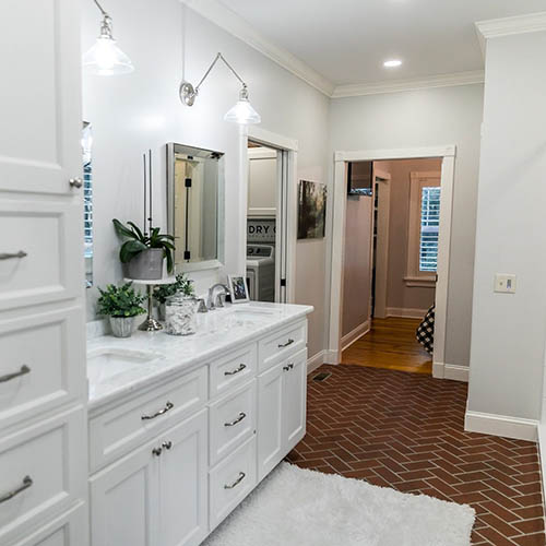 Large white renovated master bathroom with red brick floors